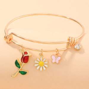 Close-up of a rose and butterfly bracelet on a wrist with flowers in the background